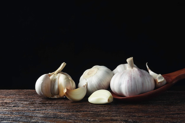 Ail blanc frais sur une table en bois avec du noir.