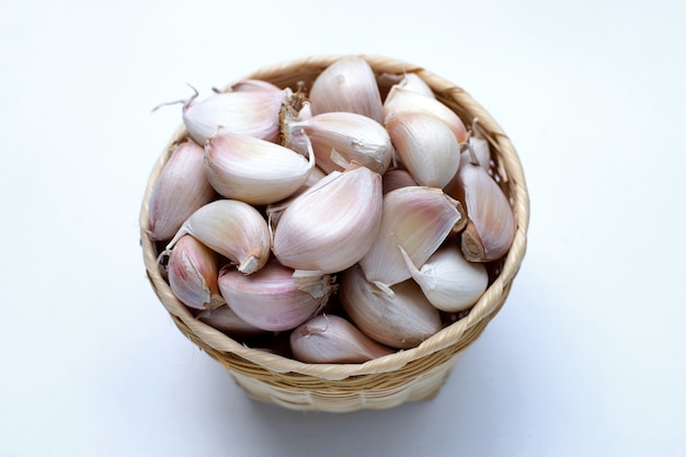 L'ail dans le panier de bambou sur fond blanc