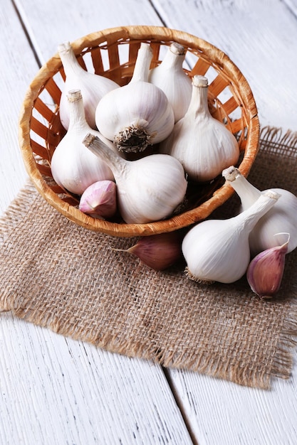 Ail frais dans un panier en osier sur fond de bois