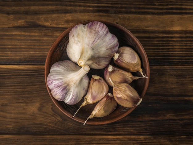 Ail frais récolté dans le jardin dans un bol sur un fond de bois