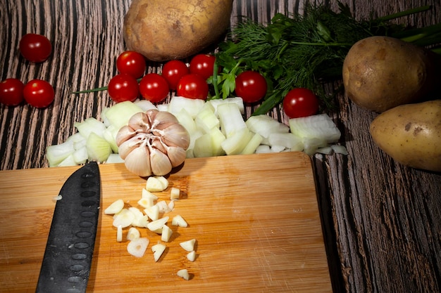 Ail sur une planche en bois à côté d'ingrédients de légumes et d'herbes pour faire de la soupe