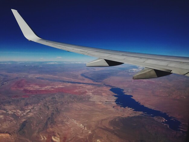 Photo aile d'avion au-dessus du paysage contre le ciel bleu