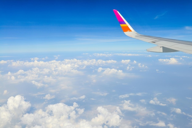 Une aile d'avion dans le ciel. Belle vue sur le ciel bleu au-dessus des nuages blancs depuis la fenêtre de l'avion. notion de vacances