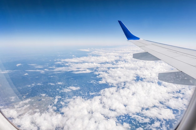 Aile d'avion depuis la fenêtre de l'avion avec vue sur le ciel bleu et les beaux nuages