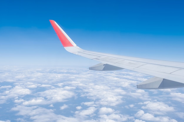 Aile d'avion, nuages et ciel bleu a vu à travers la fenêtre d'une vue d'avion.