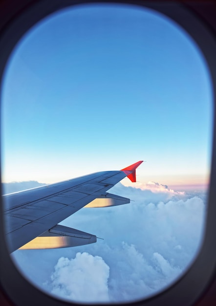 Photo aile d'avion et nuages vus à travers l'illuminateur