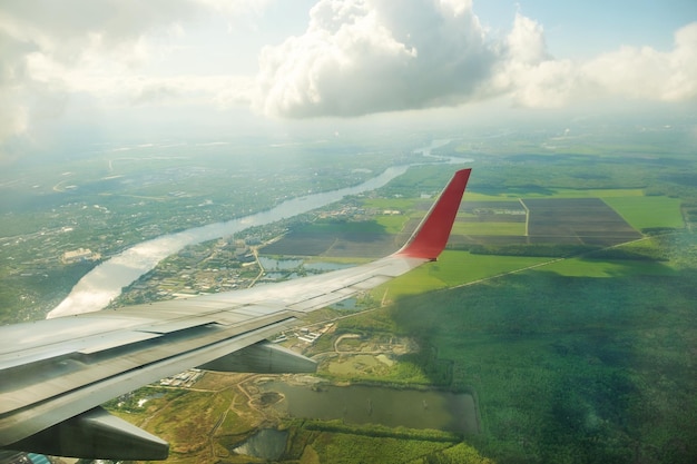 Aile du paysage d'avion ci-dessous et nuages dans le hublot