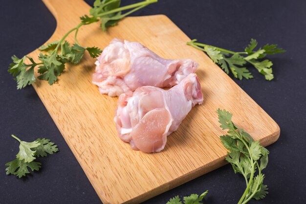 Aile de poulet frais et légumes verts sur fond de table en pierre noire.