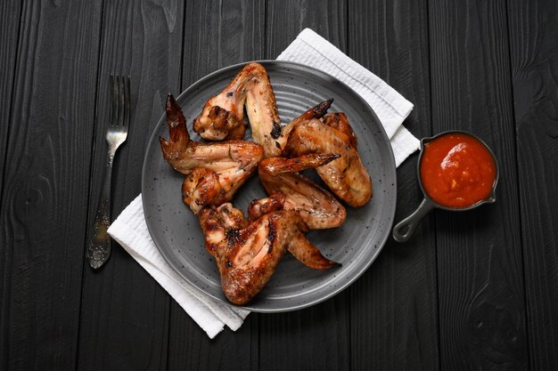 Ailes de poulet appétissantes grillées au barbecue avec des épices et des légumes jusqu'à ce qu'elles soient croustillantes