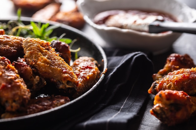 Ailes de poulet barbecue dans un plat de cuisson en fonte avec sauce barbecue et romarin.