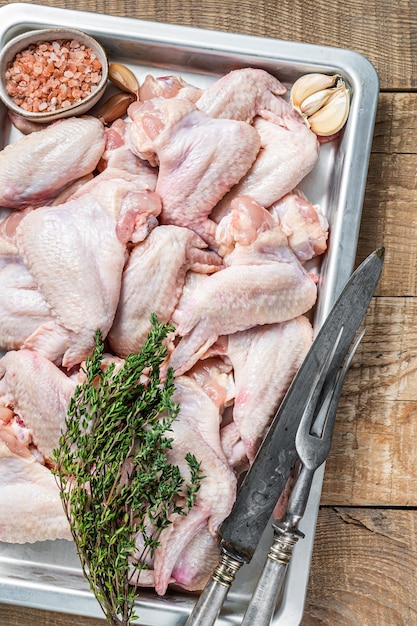 Ailes de poulet cru frais Viande de volaille dans un plateau de cuisine avec des herbes.