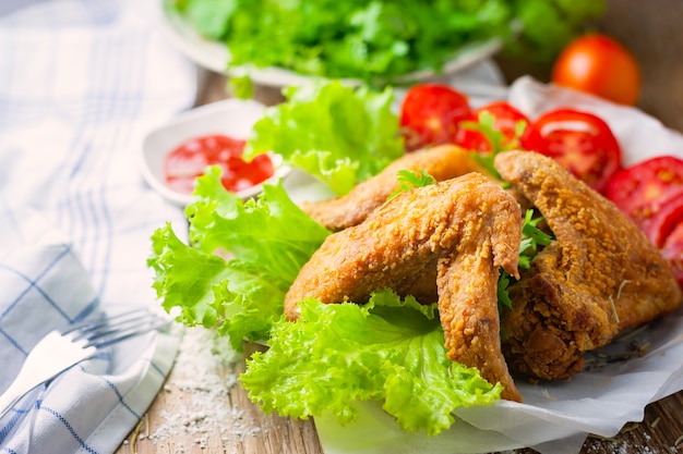 Ailes de poulet frit et ketchup sur fond en bois