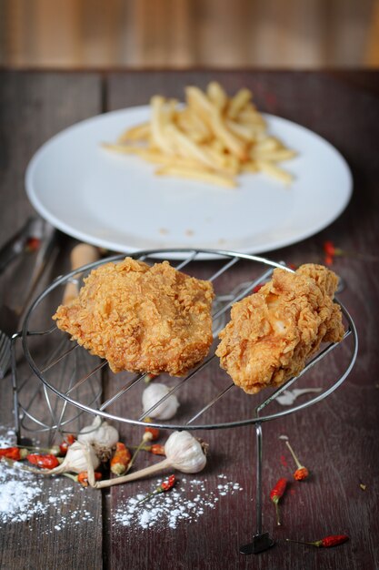 Ailes de poulet frites avec des frites sur une table en bois