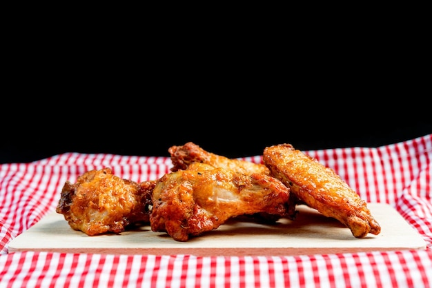 Ailes de poulet frites sur une planche à découper sur un fond noir