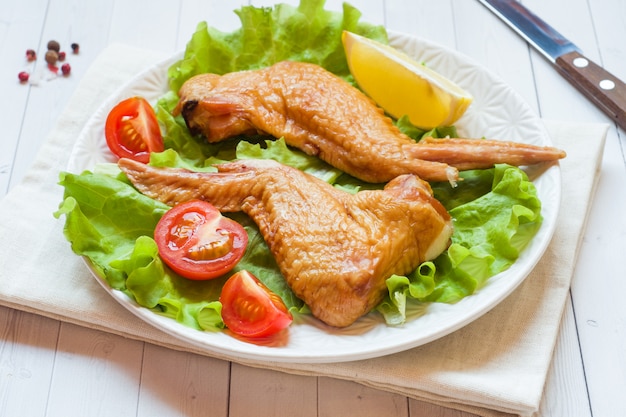 Ailes de poulet fumé avec tomate laitue fraîche et citron. Copiez l'espace.