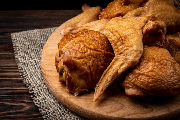 Ailes de poulet fumées sur planche de bois sur table en bois sombre.