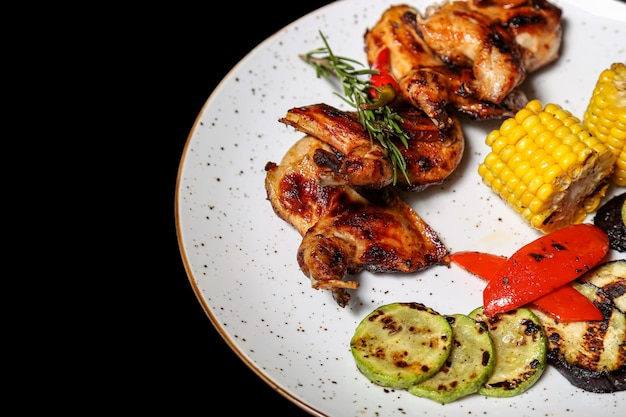 Ailes de poulet grillées aux légumes sur fond noir