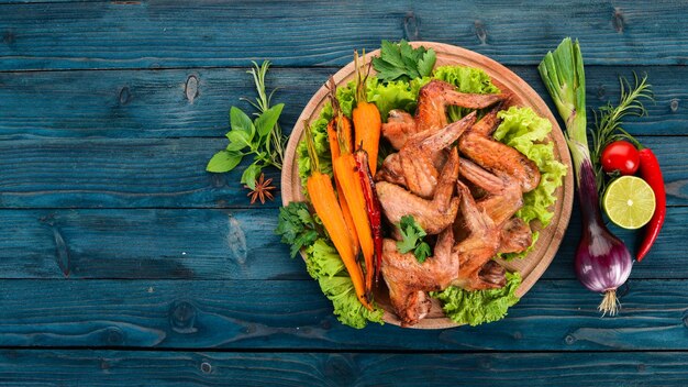 Ailes de poulet grillées avec légumes et carottes sur fond de bois Vue de dessus Espace pour copie