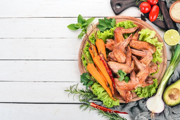 Ailes de poulet grillées avec légumes et carottes sur fond de bois Vue de dessus Espace pour copie