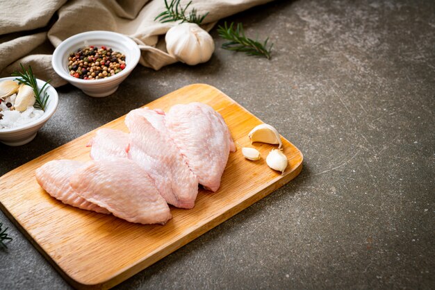 Ailes de poulet moyen cru frais sur planche de bois