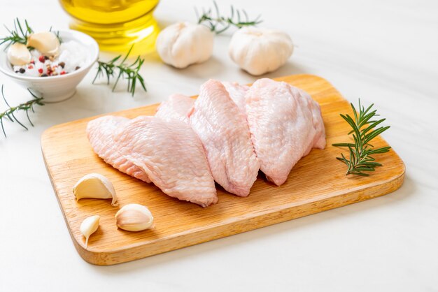 Ailes de poulet moyen cru frais sur planche de bois