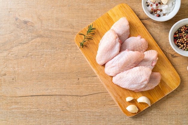 Ailes de poulet moyen cru frais sur planche de bois