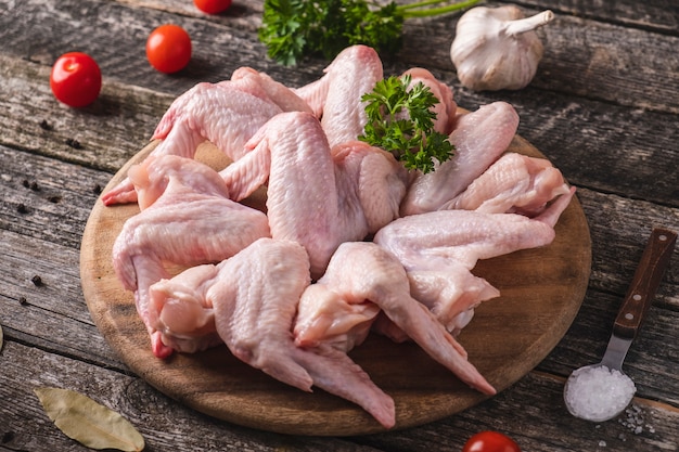 Ailes de poulet non cuites sur une planche à découper en bois d'épices. Fermer