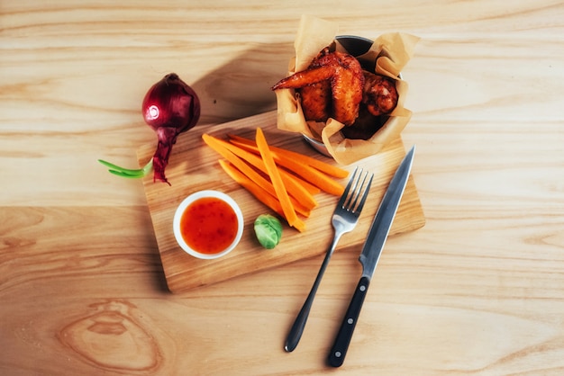 Ailes de poulet avec sauce de légumes sur une table en bois