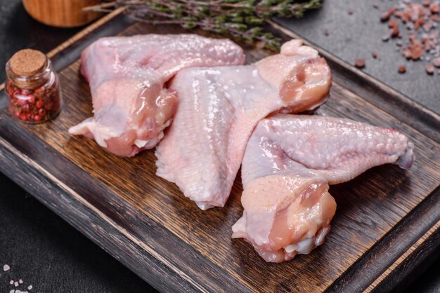 Les ailes de poulet se trouvent sur une planche de bois sur fond noir