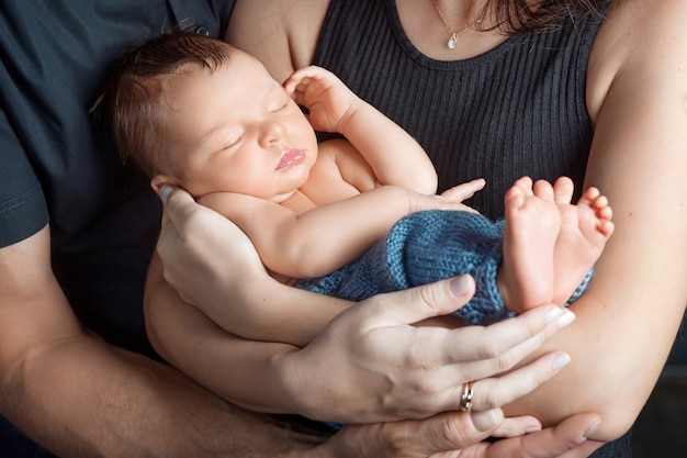 Aimer bébé qui dort dans les mains des parents. Image en gros plan. Heureuse mère et père et ils glissent bébé nouveau-né