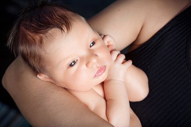 Aimer bébé avec les yeux ouverts dans les mains de la mère. Image en gros plan