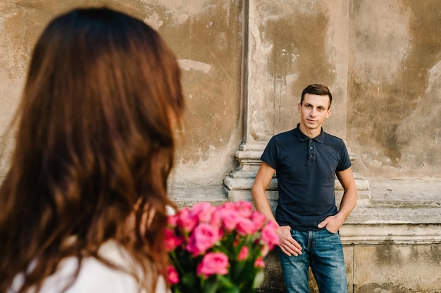 Aimer un couple heureux garçon et fille avec un bouquet de fleurs à la saint-valentin à l'extérieur Un homme et une femme marchant dans les rues de la ville