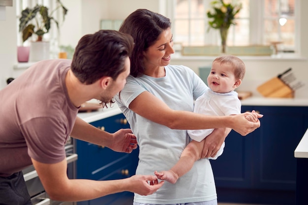Aimer la famille transgenre avec bébé dans la cuisine à la maison ensemble