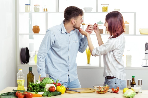 Aimer heureux couple préparer une salade saine de légumes frais dans la cuisine