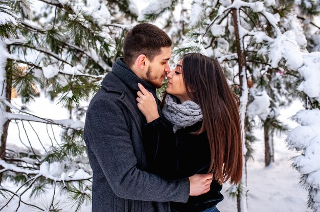 Aimer le jeune couple au repos dans une forêt enneigée. Embrasse et embrasse. concept de vacances