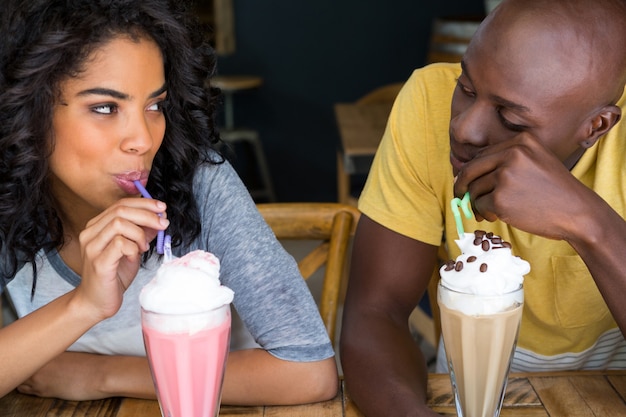 Aimer le jeune couple ayant des milkshakes à table dans un café