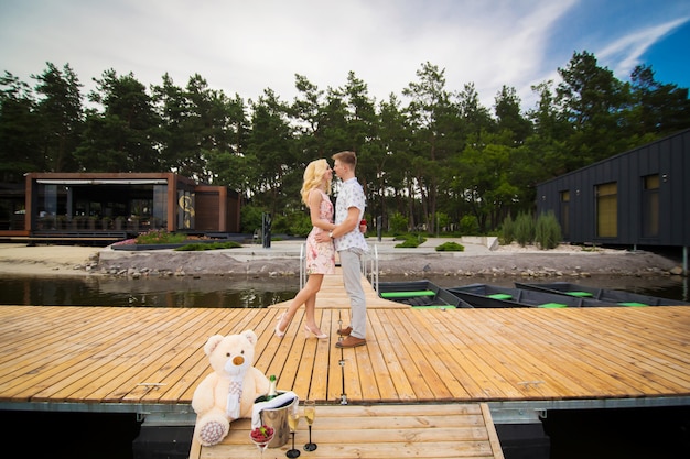 Aimer le jeune couple s'embrasse sur une jetée en bois. Histoire d'amour sur la jetée