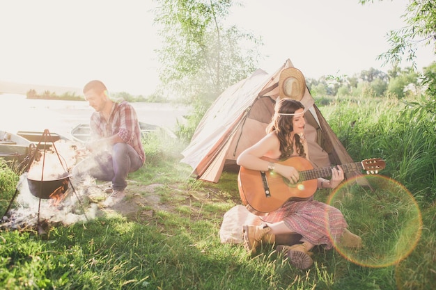 Aimer jeune couple sexy près de la tente de camp Camping couple amoureux Couples de touristes amoureux se détendre sur la nature Voyage de camping avec des amoureux Coupl insouciant près du feu de camp concept de liberté de feu de joie