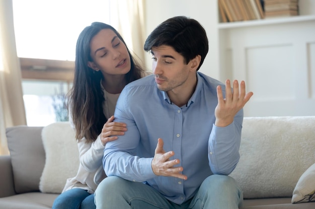 Aimer une jeune femme coupable essayant de faire la paix s'excuser après un malentendu ou une querelle avec un homme en colère offensé têtu assis ensemble sur le canapé à la maison relations familiales problèmes de crise concept
