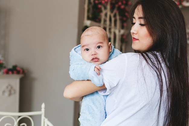 Aimer La Mère Asiatique Tenant Son Bébé à La Maison.