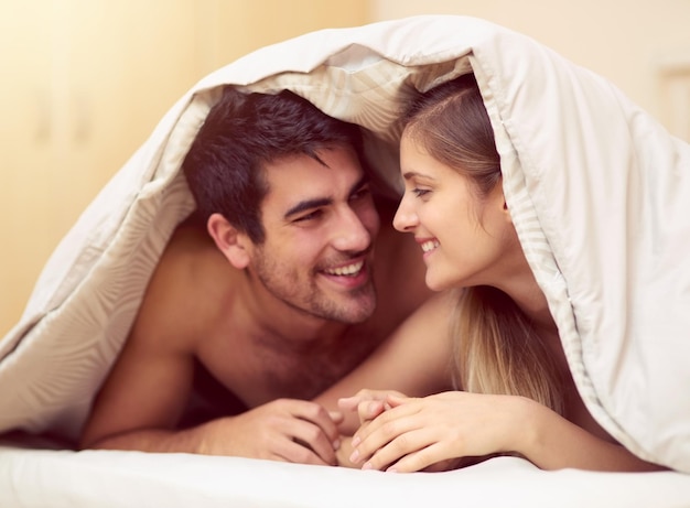 Aimez celui avec qui vous êtes Photo d'un jeune couple aimant se souriant tout en étant allongé sous une couverture ensemble