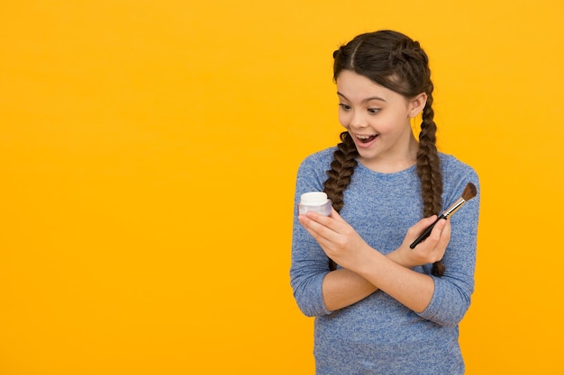 Aimez-vous plus concept de soins de la peau en appliquant du maquillage sur une peau saine enfant maquillage produits copie espace studio photo d'une fille faisant du maquillage surprise adolescente faisant du maquillage à l'aide d'un pinceau à poudre