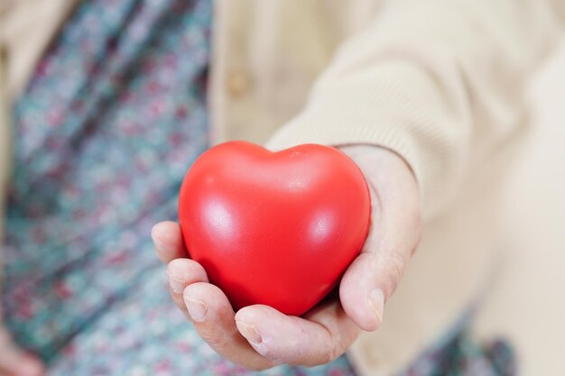 Aîné asiatique femme âgée patiente tenant un coeur rouge à l'hôpital