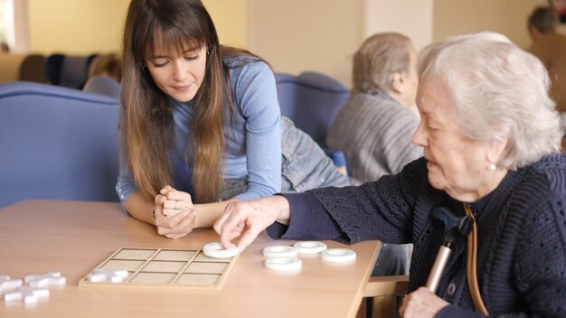 Une aînée joue à un jeu de société avec une femme.