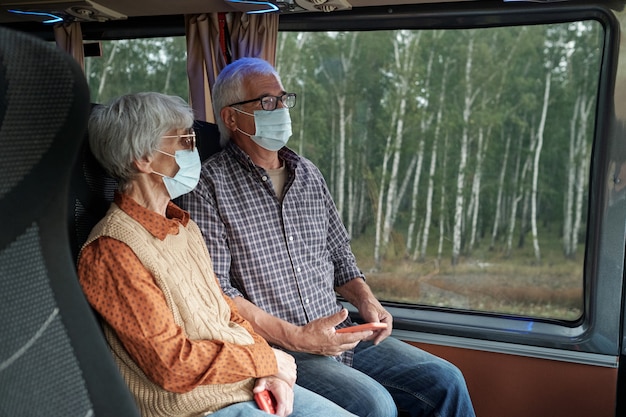 Aînés contemporains dans le bus d'équitation de masques de protection