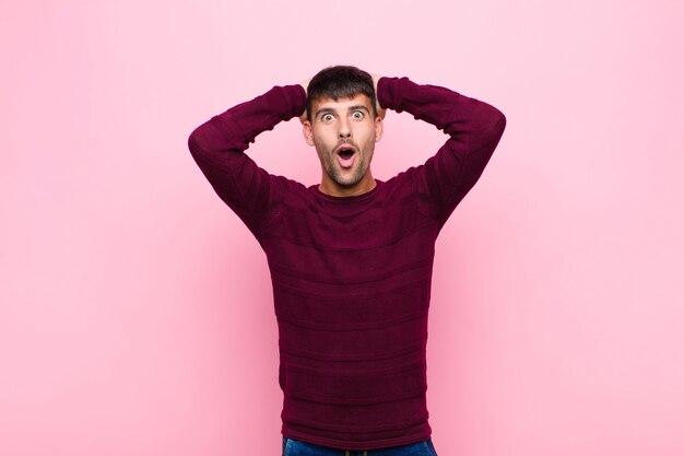 l'air excité et surpris, bouche bée avec les deux mains sur la tête, se sentant comme un heureux gagnant