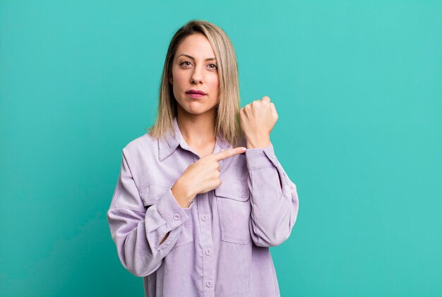 L'air impatient et en colère pointant vers la montre demandant la ponctualité veut être à l'heure