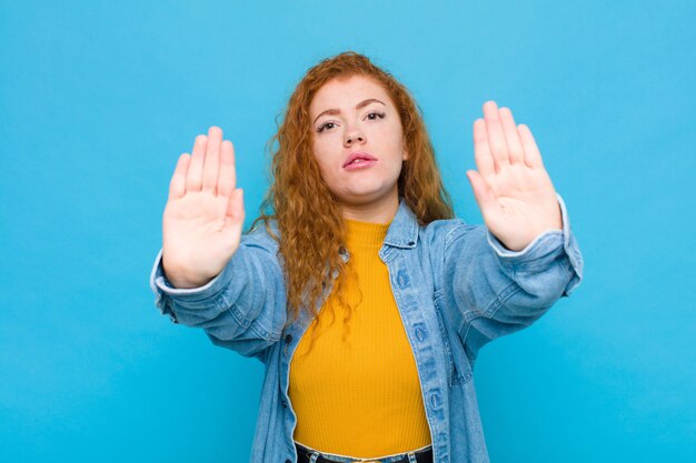 l'air sérieux, malheureux, en colère et mécontent interdisant l'entrée ou disant arrêt avec les deux paumes ouvertes