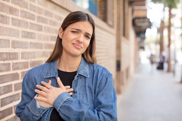 L'air triste, blessé et le cœur brisé, tenant les deux mains près du cœur, pleurant et se sentant déprimé