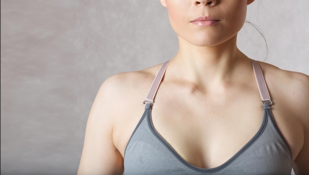 Aisselle grasse chez jeune femme entre 30 et 40 ans vêtue d'un soutien-gorge sport gris.